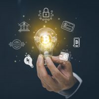 Businessman hand hold light bulb with bitcoin Cryptocurrency Investment and icons, trade, save and make a profit with interest, virtual financial chart diagram, Digital symbol of new virtual currency.